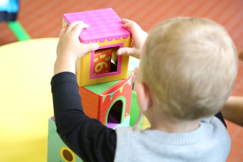 Kleinkind baut mit bunten Steckwürfeln einen Turm