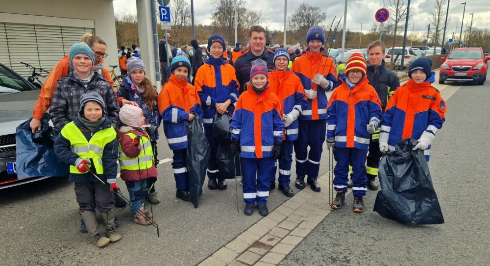 Foto mit Kindern die Zangen und Müllsäcke in der Hand halten 